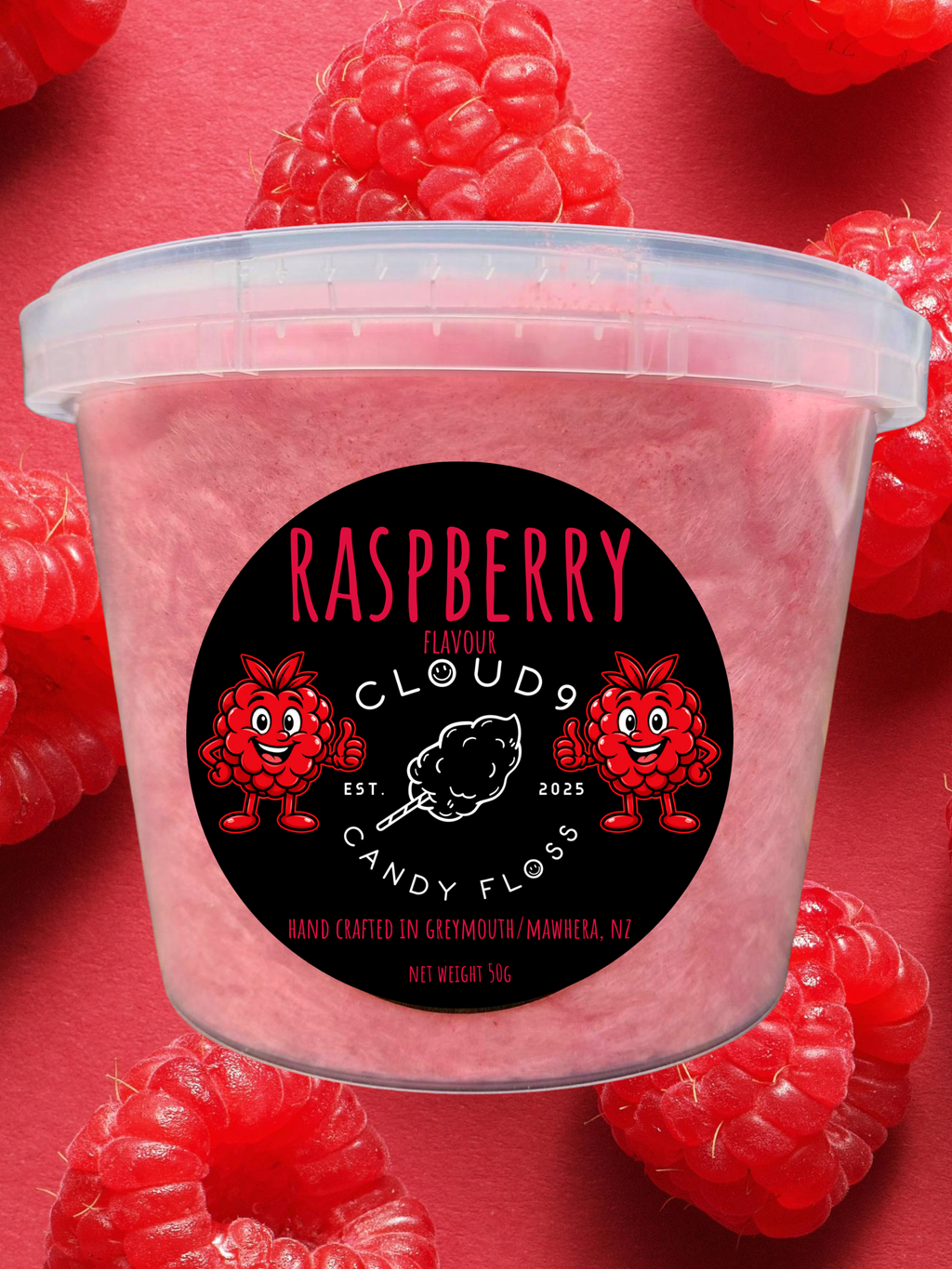 A clear plastic tub filled with pink candy floss, surrounded by fresh red raspberries on a pink background. The front label reads 'RASPBERRY CLOUD 9 CANDY FLOSS' with raspberry and cotton candy graphics.